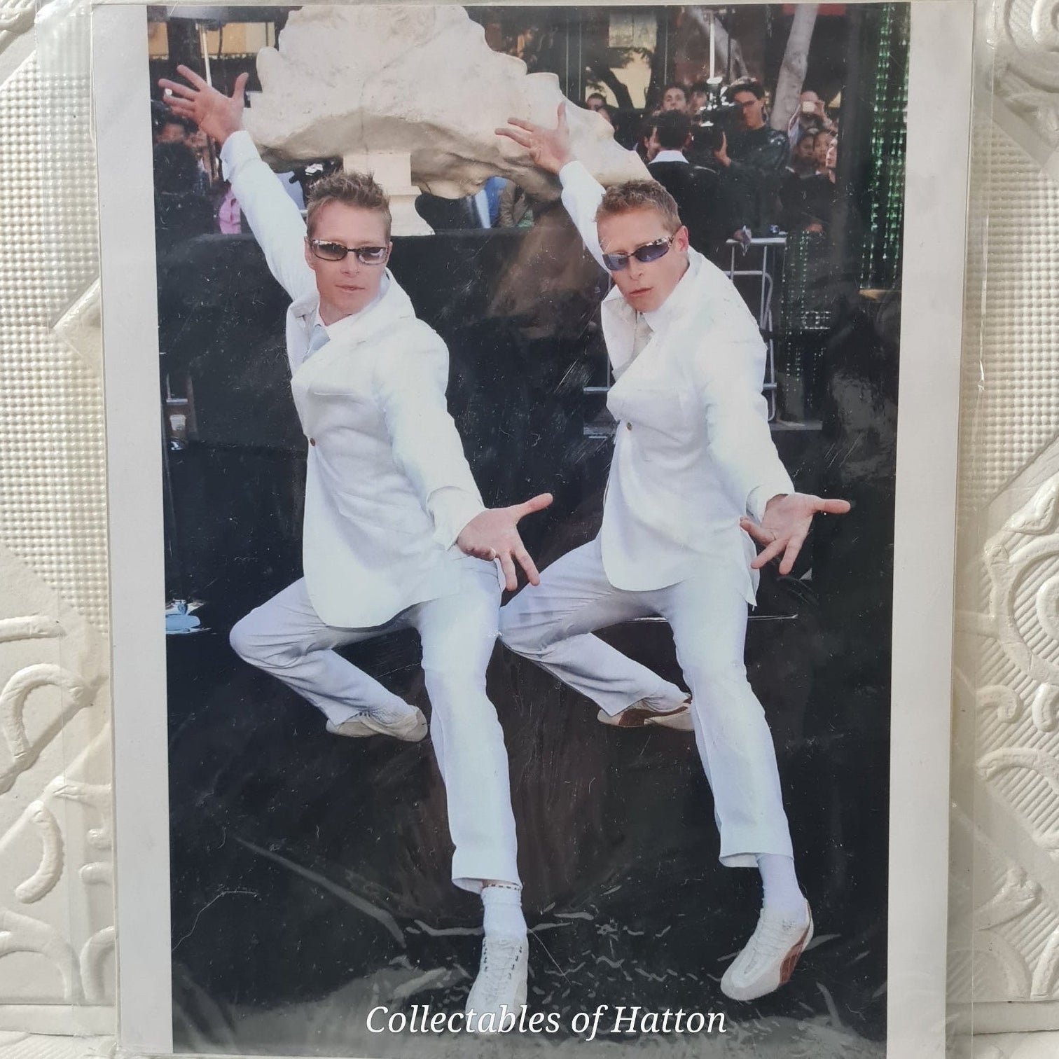 Two people in white outfits posing on a black surface with 'Collectables of Hatton' branding. matrix