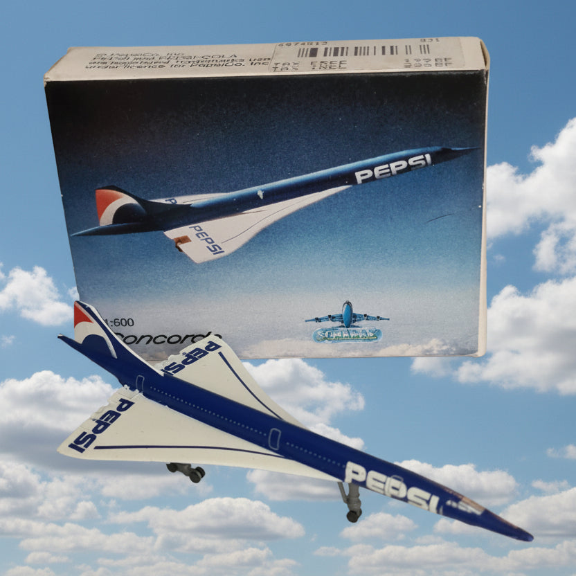 A model Concorde airplane with Pepsi branding, shown next to its printed packaging box on a light-colored surface.